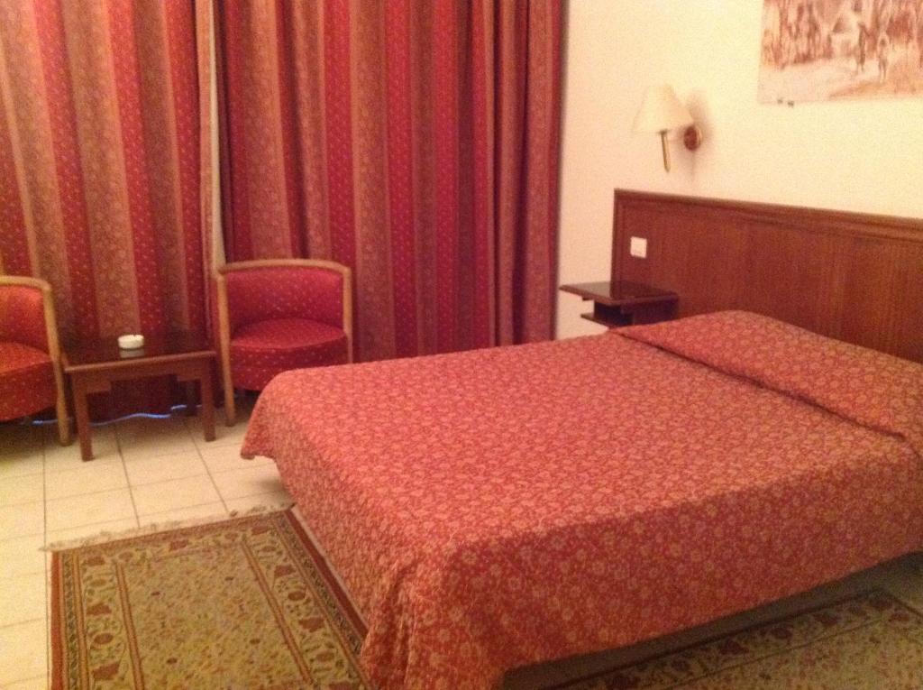 a hotel room with a bed and two red chairs at El Hana International in Tunis