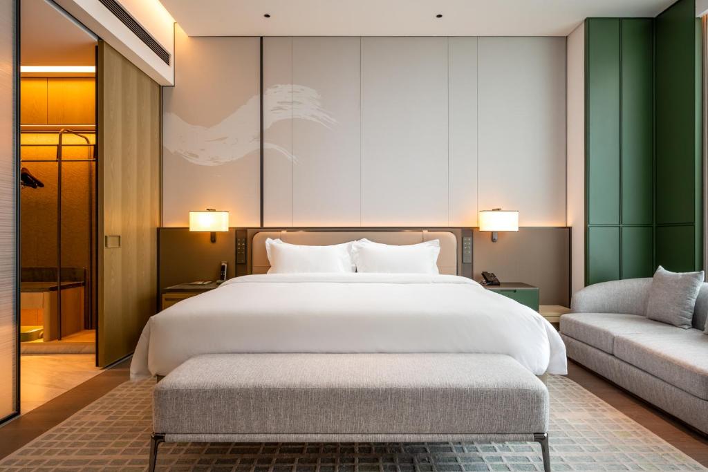 a bedroom with a large white bed and a couch at Qinglian Jinghe Hotel Wuhan Zoo International Expo Center Branch in Han-yang-hsien