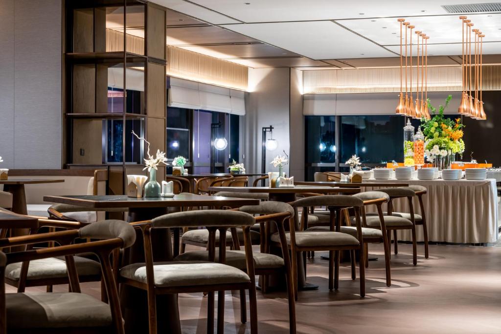a restaurant with tables and chairs in a room at Qinglian Jinghe Hotel Wuhan Zoo International Expo Center Branch in Han-yang-hsien