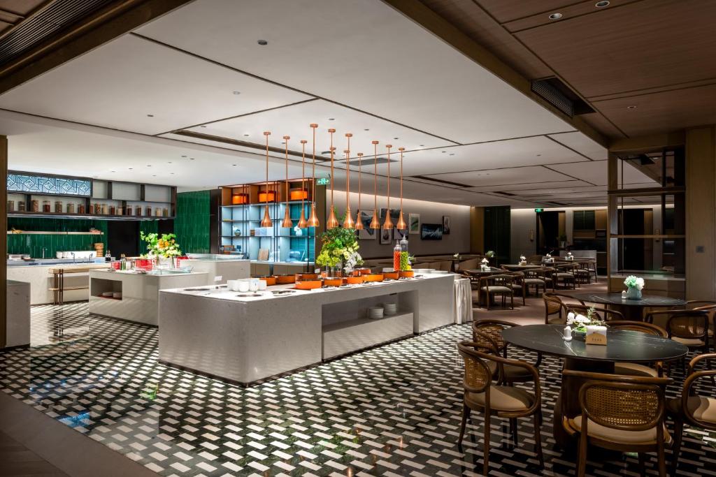 a restaurant with tables and chairs in a room at Qinglian Jinghe Hotel Wuhan Zoo International Expo Center Branch in Han-yang-hsien