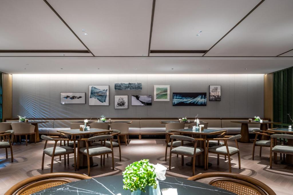 a restaurant with tables and chairs in a room at Qinglian Jinghe Hotel Wuhan Zoo International Expo Center Branch in Han-yang-hsien