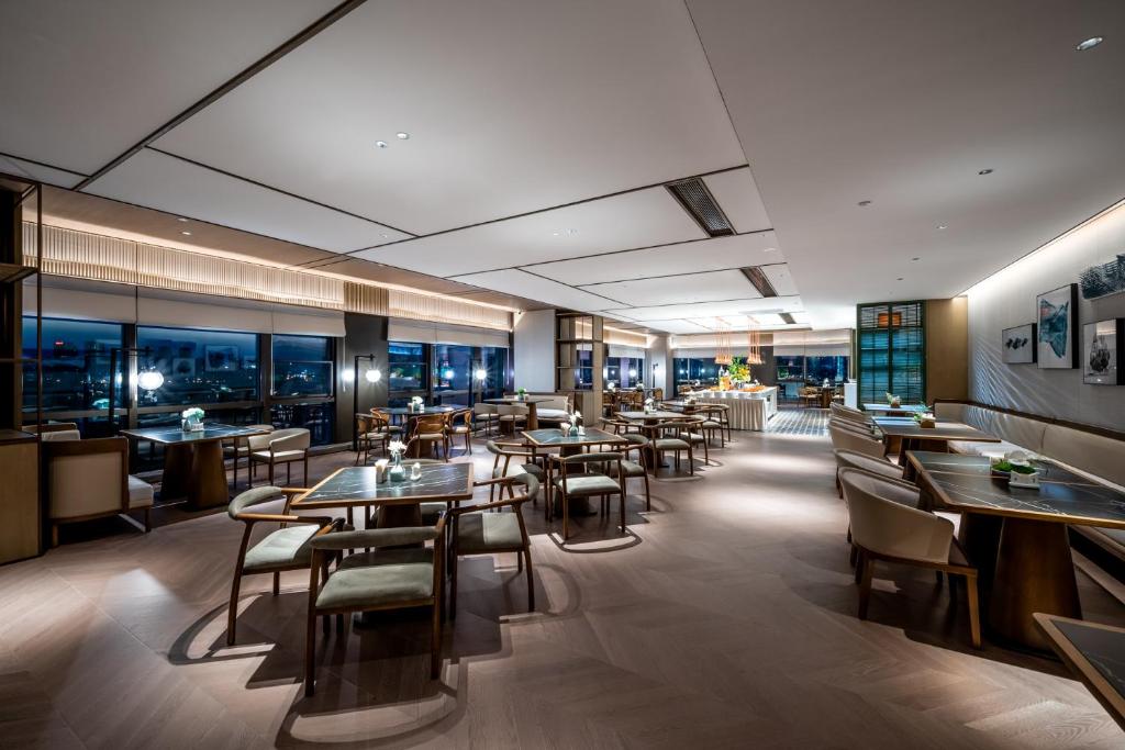 a restaurant with tables and chairs and windows at Qinglian Jinghe Hotel Wuhan Zoo International Expo Center Branch in Han-yang-hsien