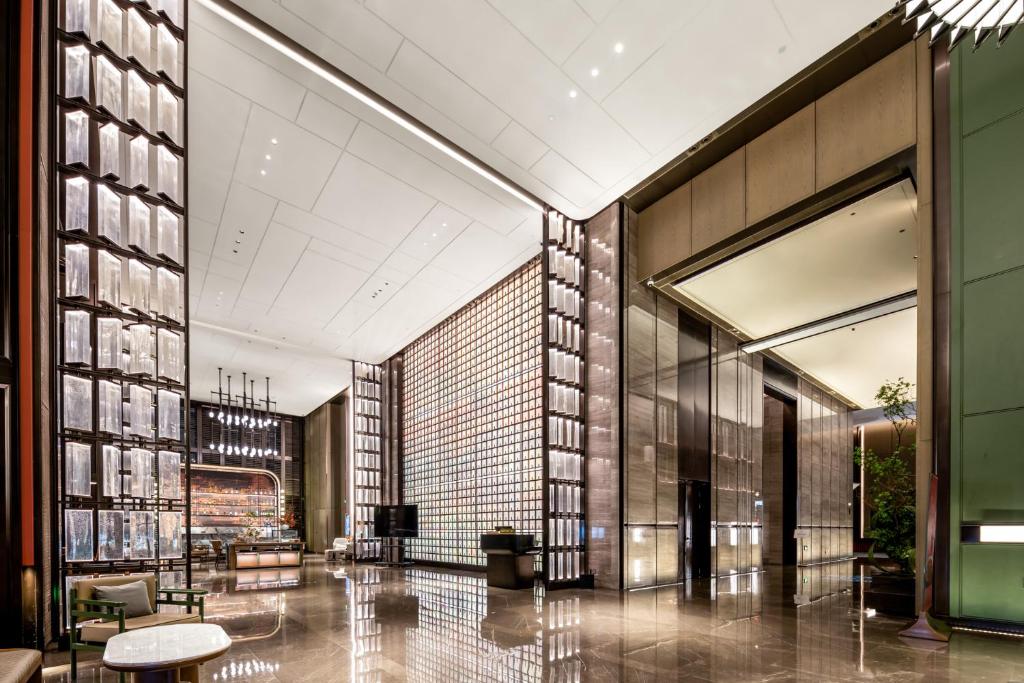a lobby of a building with tables and chairs at Qinglian Jinghe Hotel Wuhan Zoo International Expo Center Branch in Han-yang-hsien
