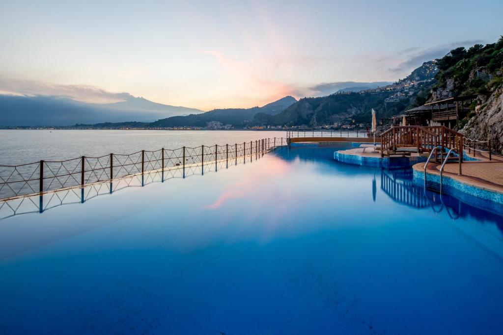 a swimming pool next to a body of water at UNA HOTELS Capotaormina in Taormina