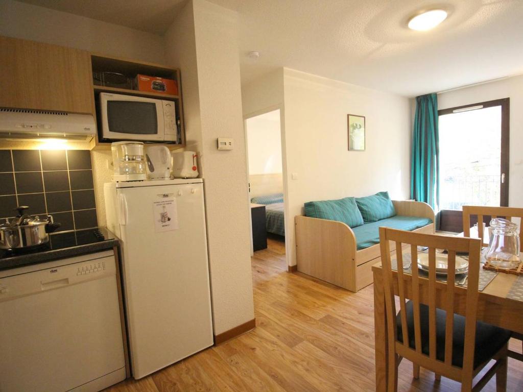 uma cozinha e sala de estar com um frigorífico e uma mesa em Charmant T2 avec balcon, parking et lave-linge près du parc - FR-1-313-235 em Luchon
