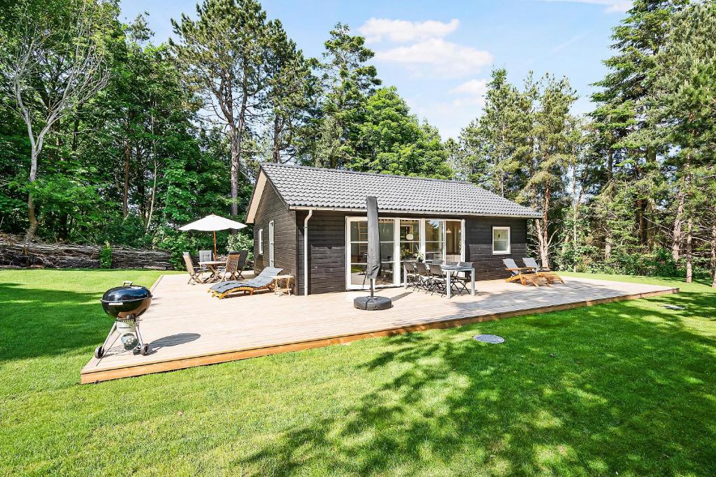 a small cabin with a deck in a yard at Beautiful Newly Built House In Lovely Surroundings in Ebeltoft