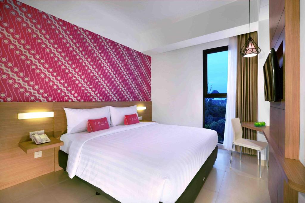 a bedroom with a large bed with a red wall at favehotel Malioboro - Yogyakarta in Yogyakarta