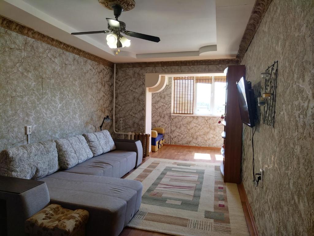 a living room with a couch and a ceiling fan at Тихий уголок in Aktau