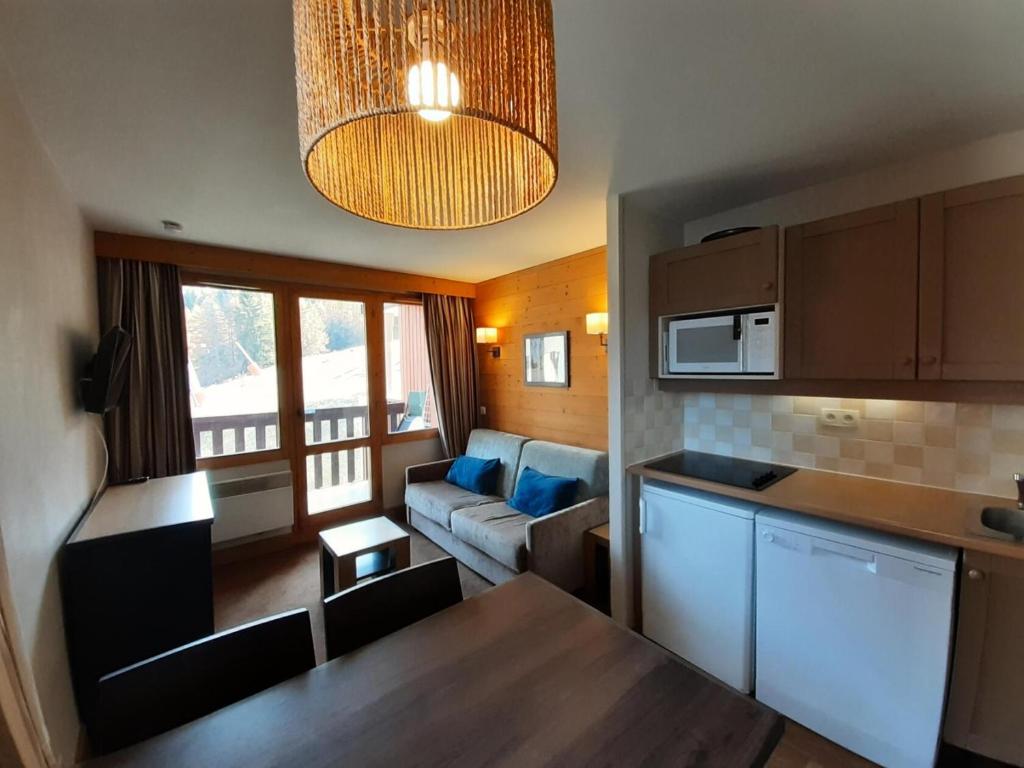 une cuisine et un salon avec un canapé et une table dans l'établissement Résidence La Marelle et Le Rami - maeva Home - Appartement 2 pièces 4 personnes - Sélection MAE-0924, à La Plagne Tarentaise