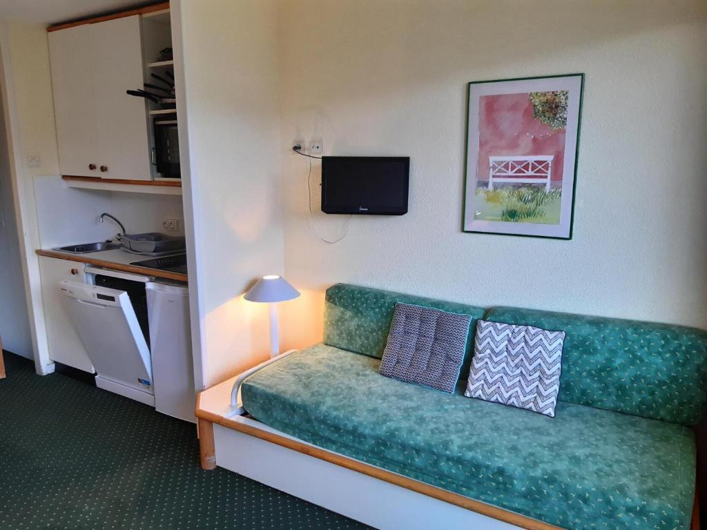 - un salon avec un canapé vert dans l'établissement Résidence Le Sextant - maeva Home - Appartement 2 pièces 5 personnes - Sélection MAE-9811, à La Plagne Tarentaise