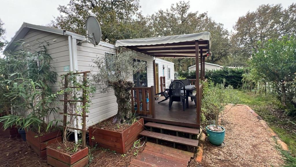 une petite maison avec un porche et une terrasse dans l'établissement Mobil-home 316 3 chambres domaine de la forge 4 étoiles bassin arcachon, à La Teste-de-Buch