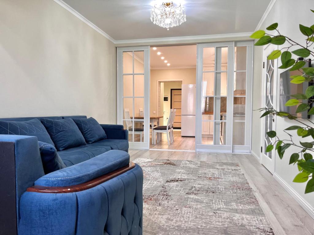 a living room with a blue couch and a table at Premium Residence, steps to center Arbat, drinking water as a gift in Almaty
