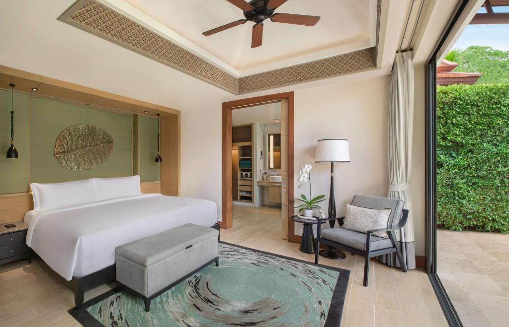 a bedroom with a white bed and a chair at Banyan Tree Phuket in Bang Tao Beach