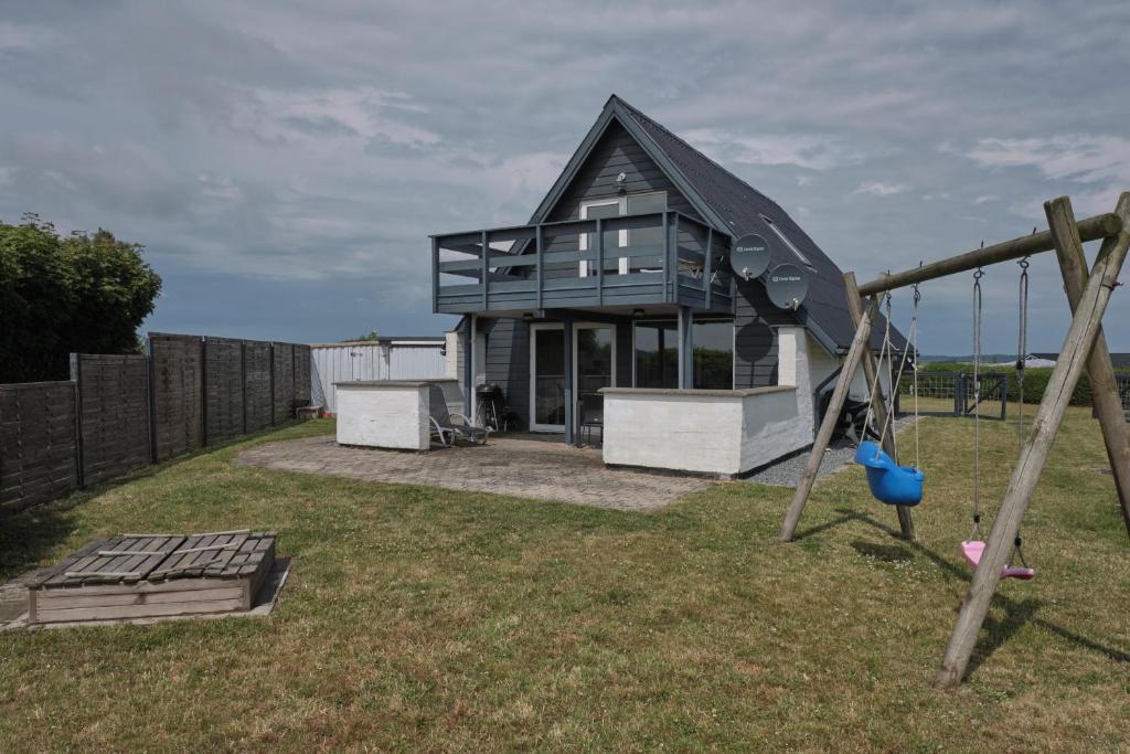 ein Haus mit einem Spielplatz und einer Schaukel in der Unterkunft Nice Home In Ebeltoft With 4 Bedrooms, Sauna And Wifi in Ebeltoft