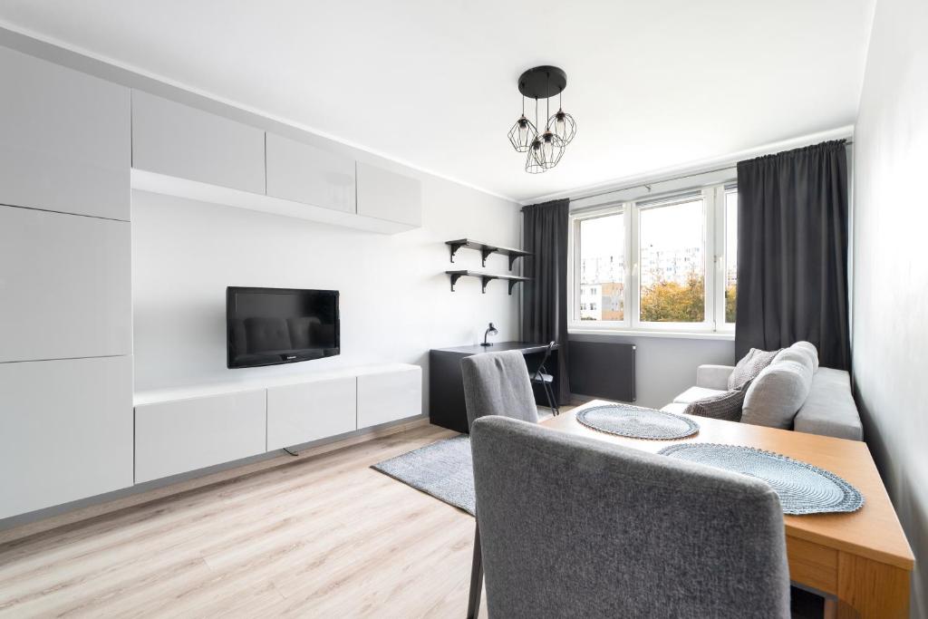 a white living room with a table and a tv at Simple Nook, Gdańsk Wejhera by Real Apartments in Gdańsk