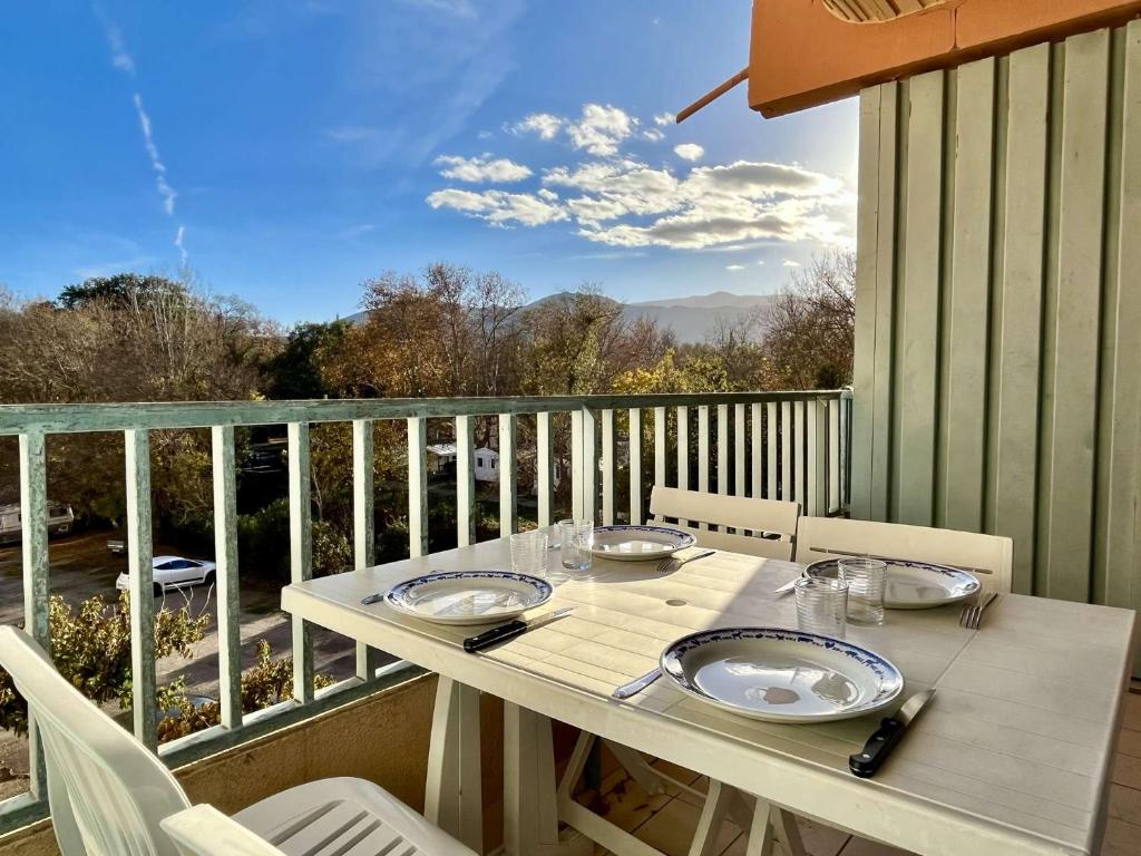d'une table blanche avec des assiettes sur un balcon avec vue. dans l'établissement Appartement Studio 4 couchages ARGELES SUR MER AR730-110, à Argelès-sur-Mer