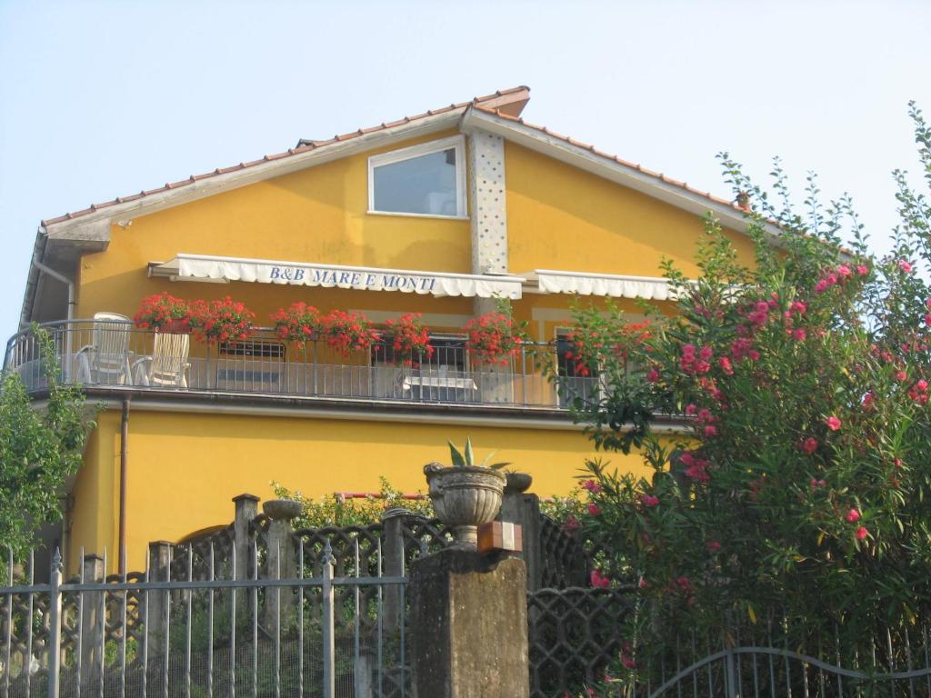 una casa amarilla con flores en el balcón en B&B Mare e Monti en La Spezia