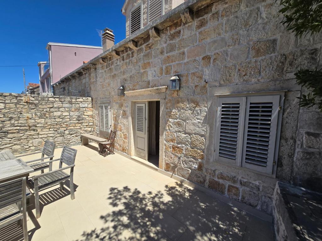 a stone building with two chairs and a bench on a patio at Maison Marmont in Vela Luka