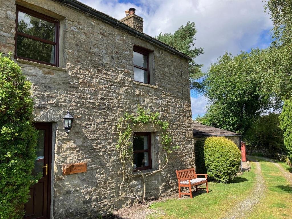 an old stone house with a bench in front of it at 1 Swollowholm Cottage in Richmond