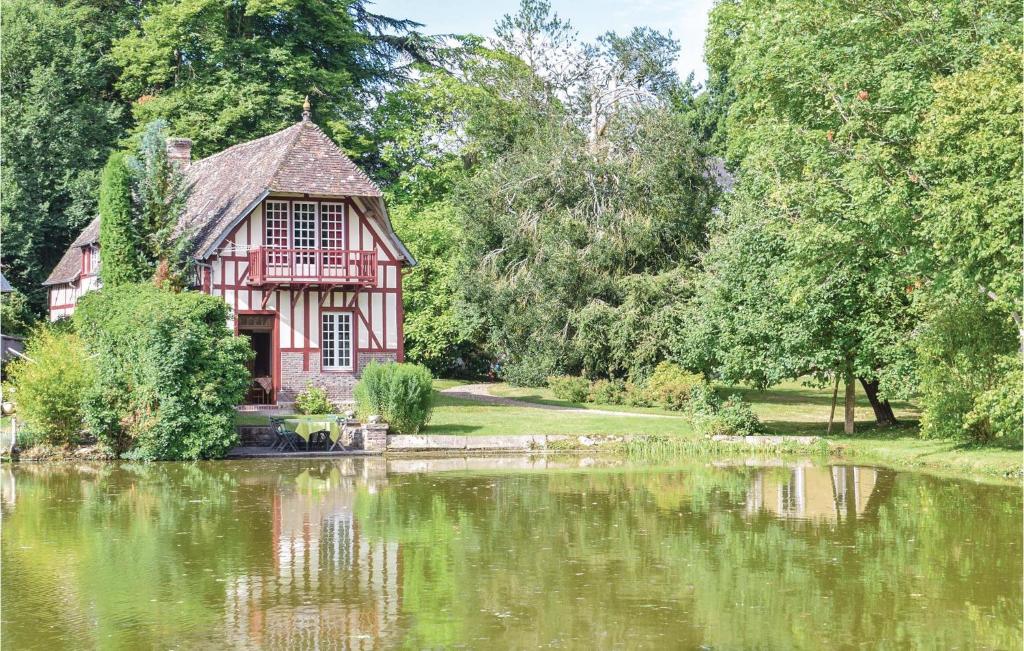 an old house next to a lake with trees at Maison Du Lac in Beaumontel