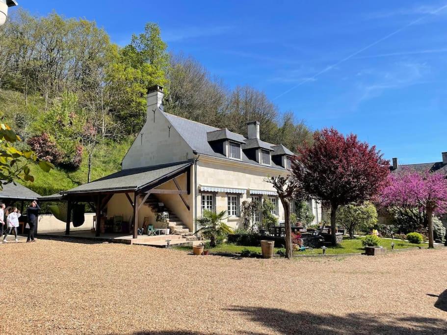 Une grande maison avec des gens qui marchent devant elle dans l'établissement Longère de Charme, bord de Loire, à Gennes