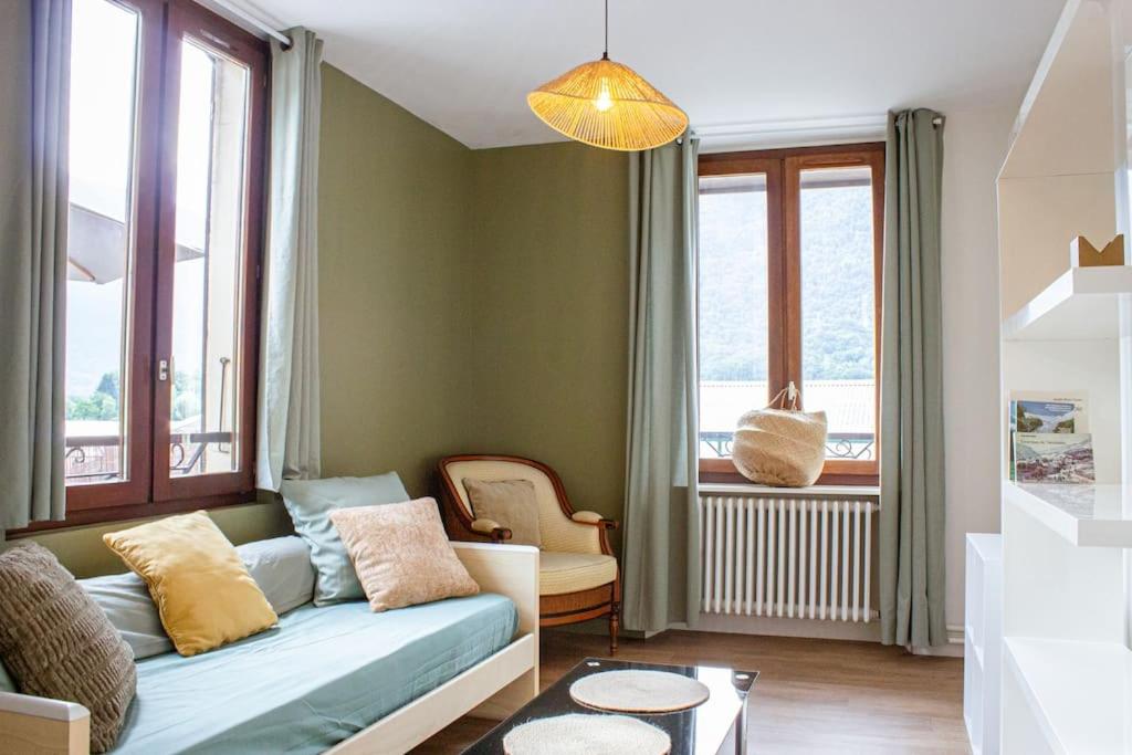 a living room with a blue couch and windows at Le montagnard - Nature, parking in Albertville