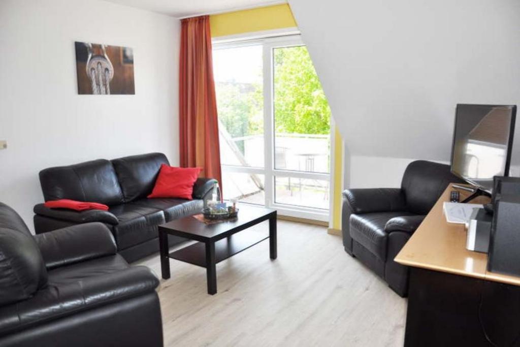 a living room with black leather furniture and a tv at Takelage - Sonniger Balkon & Gartenidylle - perfekt mit Hund in Gollendorf