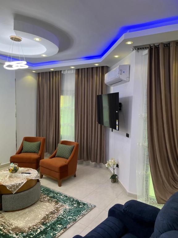 a living room with two chairs and a tv at Pyramid Heights Apartments in Cairo
