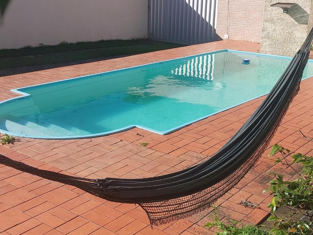 a hammock around a swimming pool on a brick patio at Quarto em Guarapari 5 min da praia in Guarapari