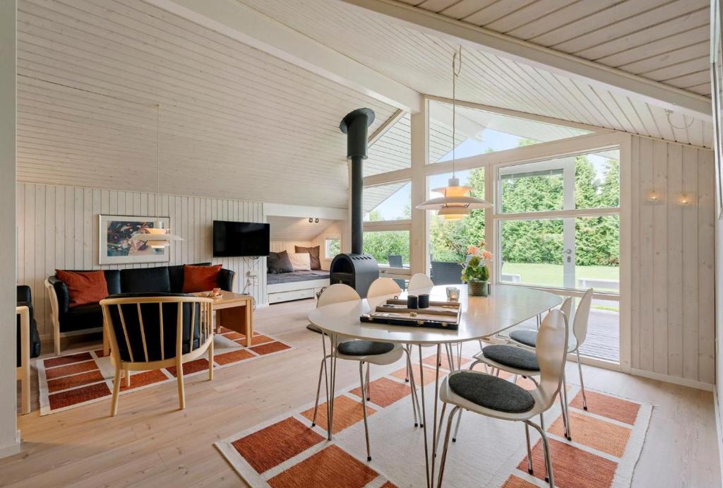 a dining room and living room with a table and chairs at Summer House Close To Nature And Beach in Dronningmølle