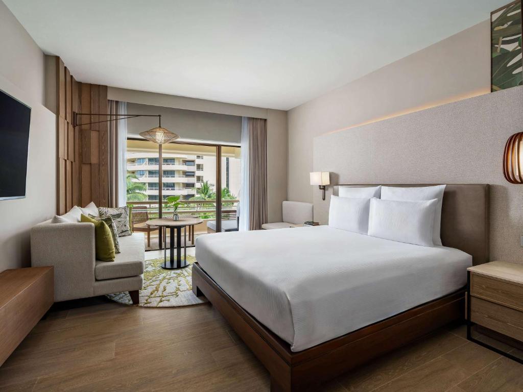 a hotel room with a large bed and a chair at Pullman Phuket Karon Beach Resort in Karon Beach