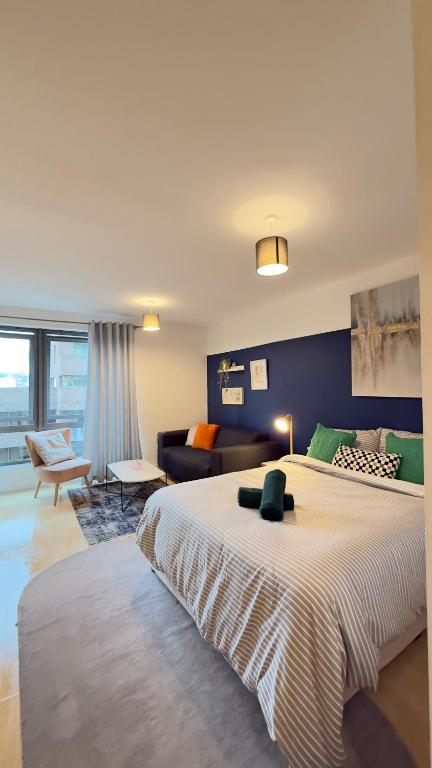 a bedroom with a large bed and a living room at Modern spacious Studio opposite station II in London