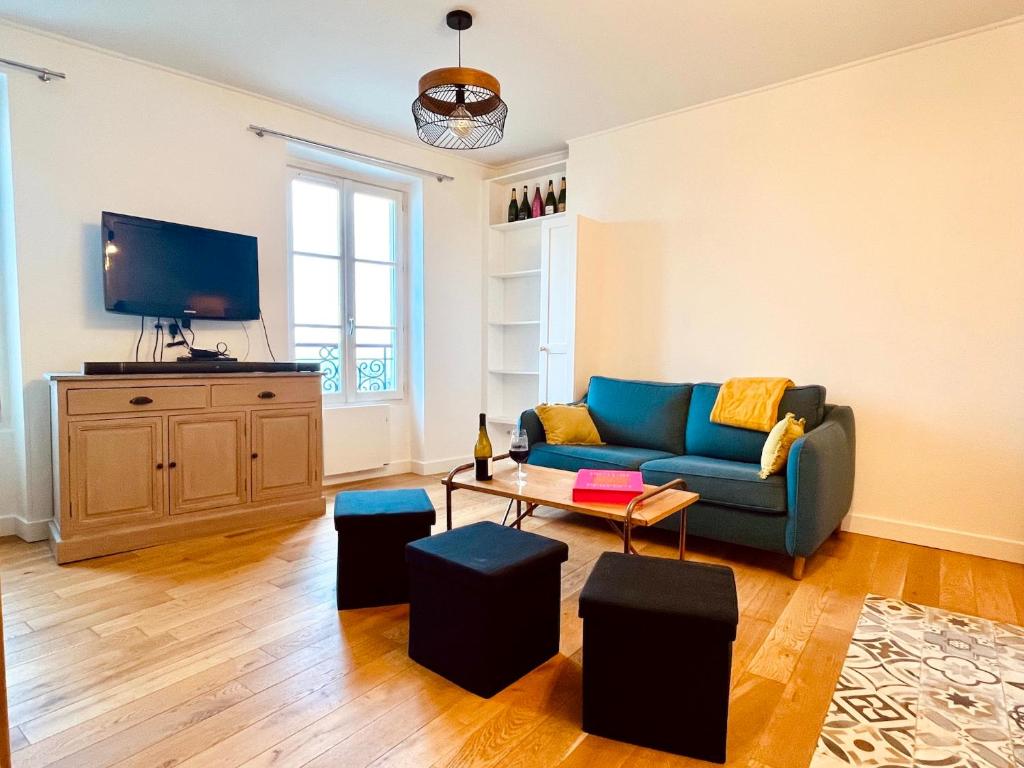 un salon avec un canapé bleu et une télévision dans l'établissement Le Penthouse du Sacré-Coeur, à Paris