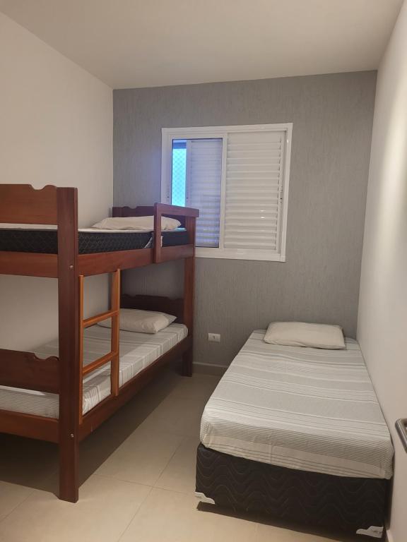a bedroom with two bunk beds and a window at APARTAMENTO PRÓXIMO A PRAIA PISCINA E AREA GOURMET in Ubatuba