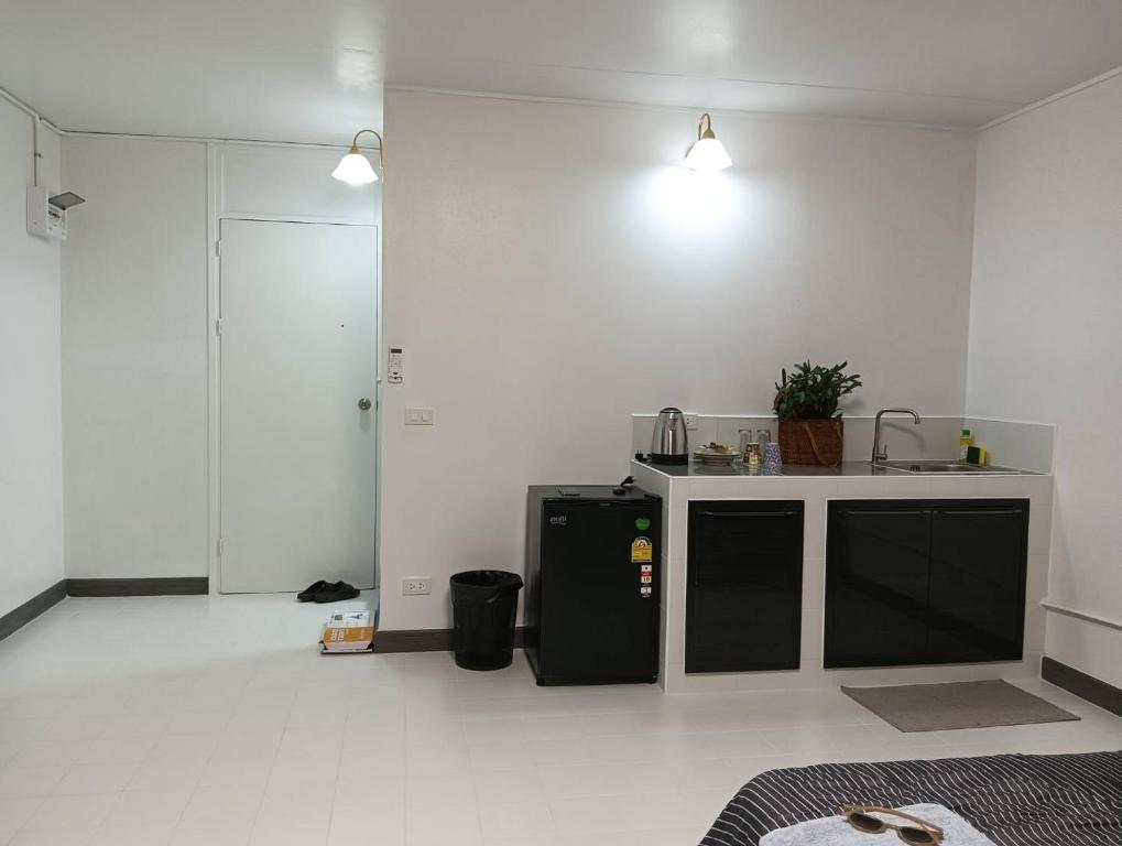 a white kitchen with a black refrigerator and a counter at Popular Muang Thong Thani Condo, Building T9, Floor 8, Room 13 in Pak Kret