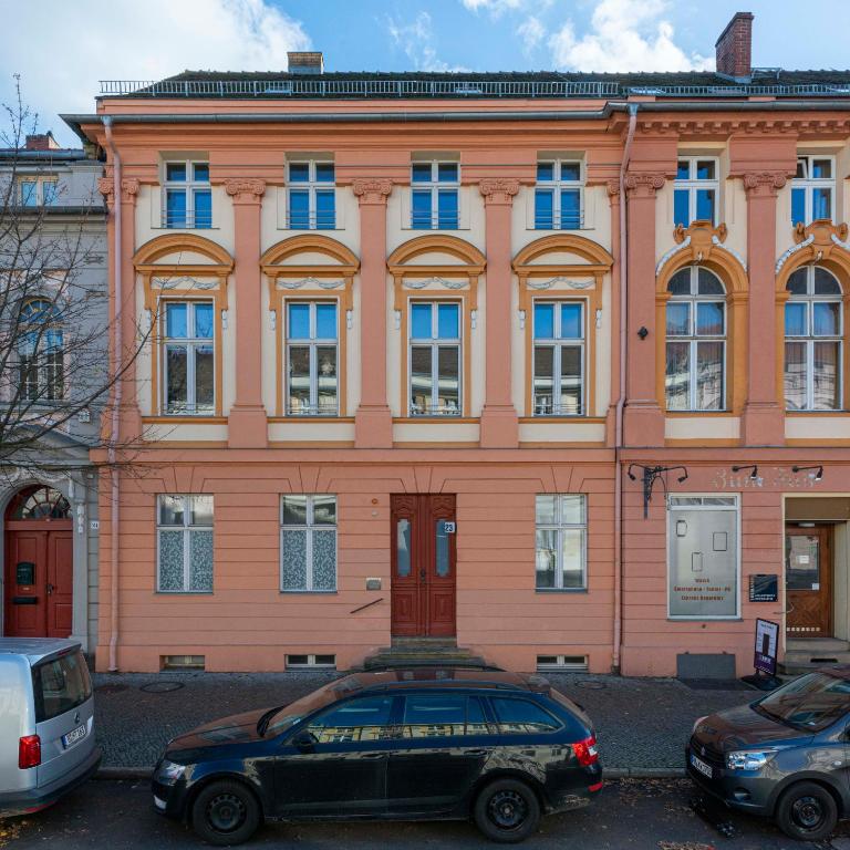 a large orange building with cars parked in front of it at Studio Apartment im Palais Fleur Blanche in Potsdam