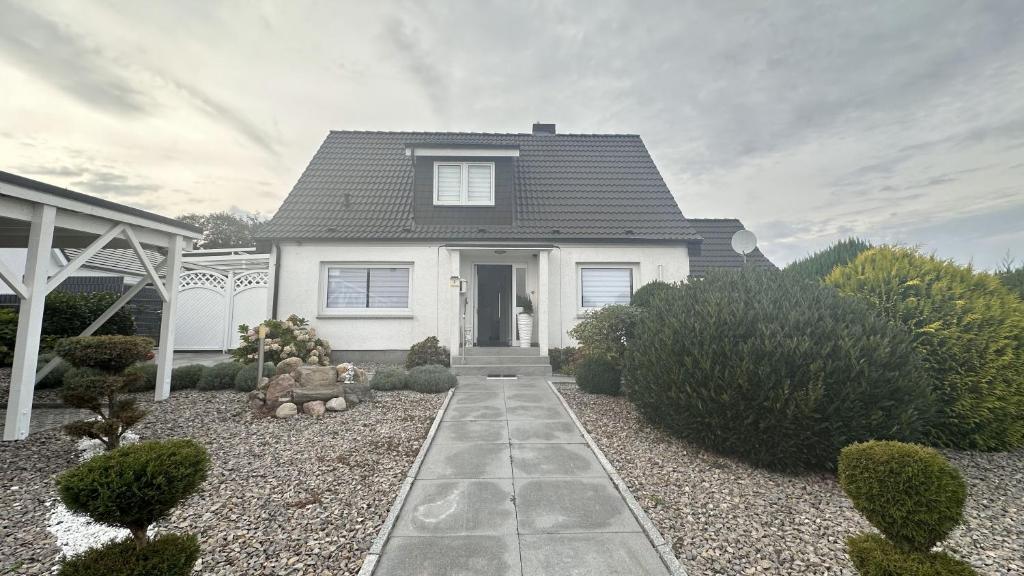 a white house with a pathway in front of it at Ferienhaus Achterhus für Familien & Homeoffice in Ratekau