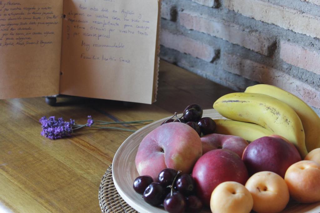 einen Obstteller auf einem Tisch neben einem Buch in der Unterkunft La Caseja de Ayllón in Ayllón