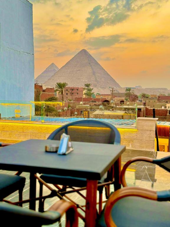 a table and chairs with a view of the pyramids at Pyramids Enigma Grand Lodge in Cairo