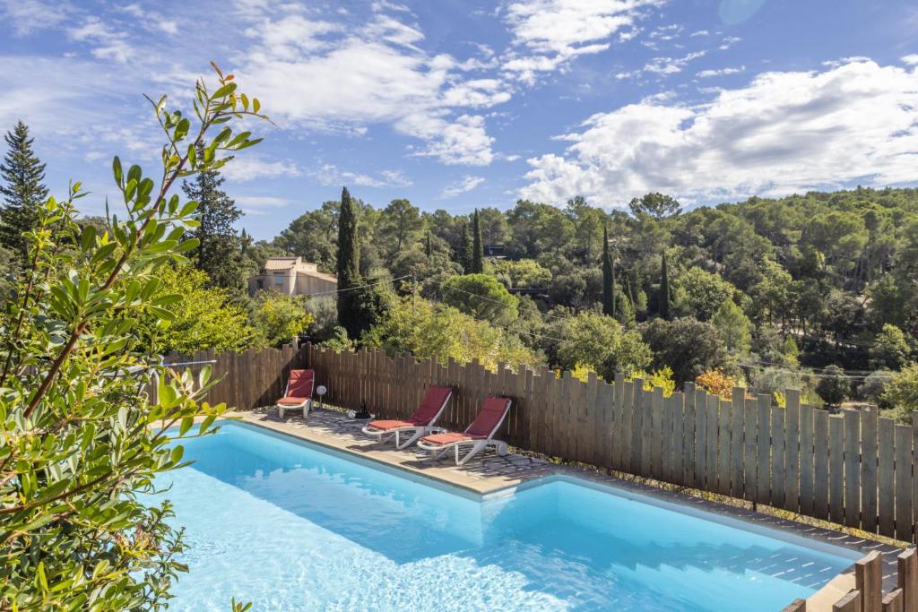 une piscine avec deux chaises et une clôture dans l'établissement Gîte Nature, à Lorgues