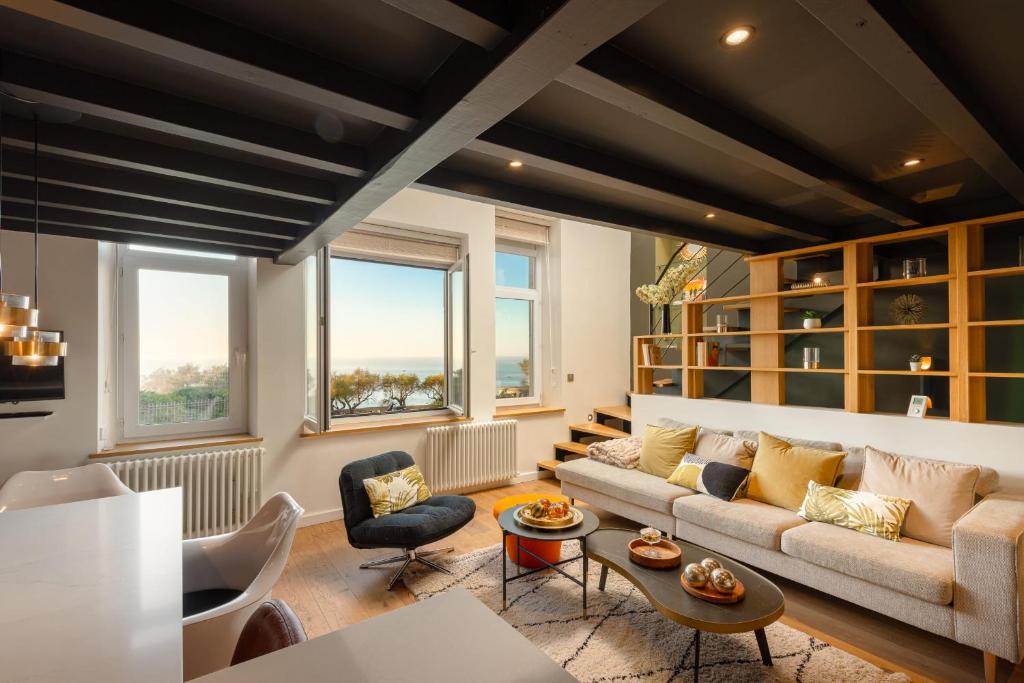 un salon avec un canapé, des chaises et des fenêtres dans l'établissement ALMA - Apartment with terrace and sea view in Biarritz, à Biarritz