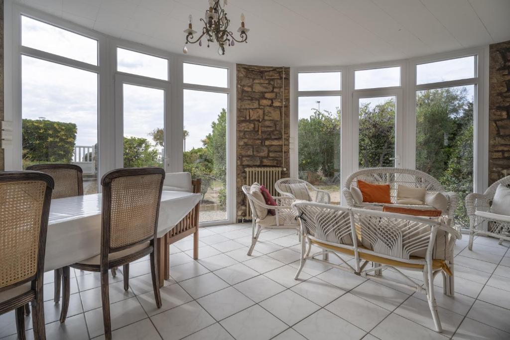 une salle à manger avec une table, des chaises et des fenêtres dans l'établissement Magnifique Villa plage à 20m, à Saint-Cyr-sur-Mer