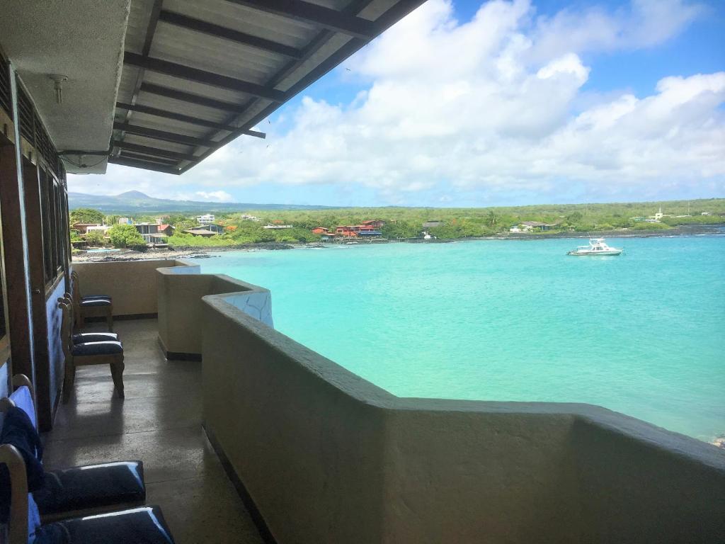 uma varanda com vista para o mar e um barco em Hostal Estrella de Mar em Puerto Ayora