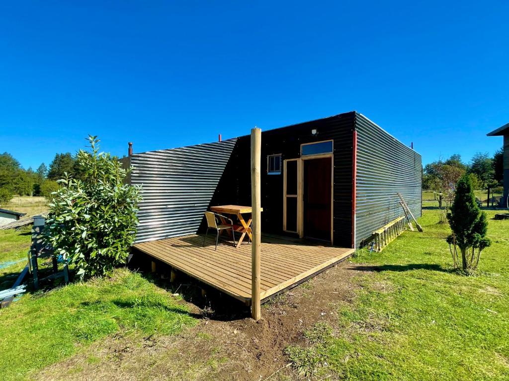 a small cabin with a table on a deck at TinyHouse Box Lican Ray in Licán Ray