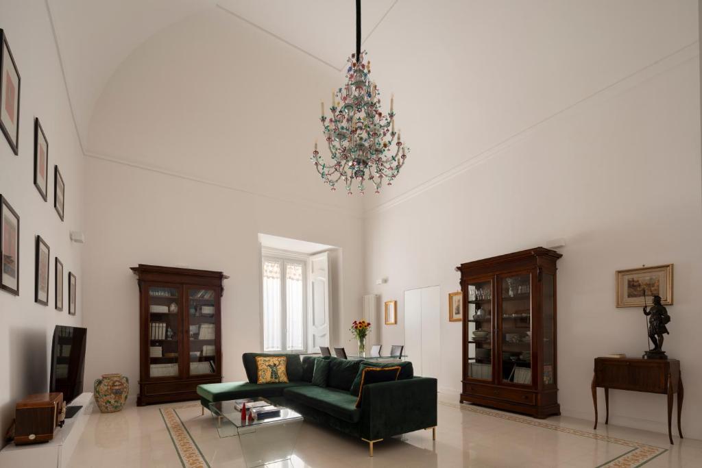 un soggiorno con divano verde e lampadario pendente di A.RI.EL luxury apartment a Napoli