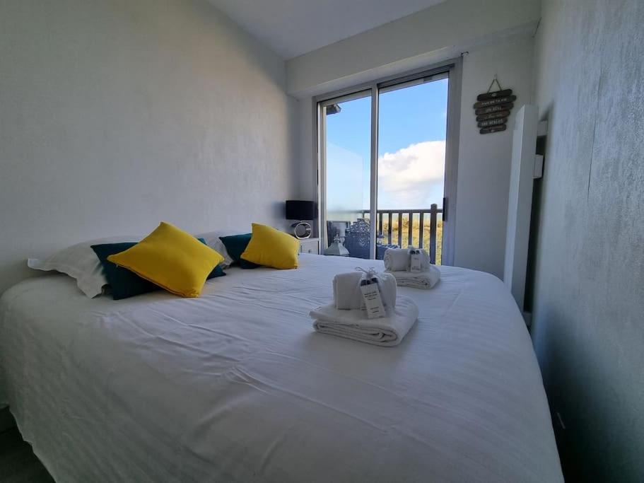 - une chambre dotée d'un grand lit avec des oreillers jaunes et bleus dans l'établissement Cap au Large-Vue Mer Panoramique, à Cabourg