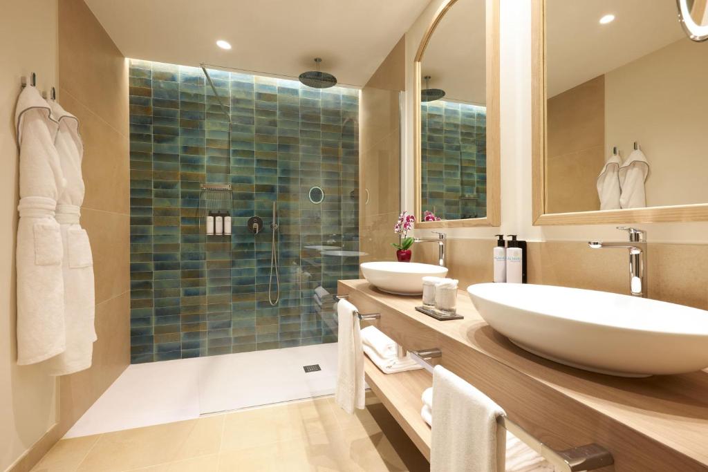 a bathroom with two sinks and a shower at Almar Timi Ama Resort & Spa in Villasimius