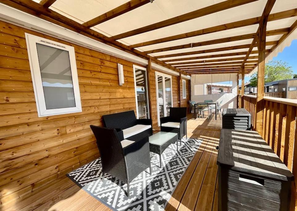 une terrasse avec des chaises et un banc sur une maison dans l'établissement Bungalow neuf avec belle terrasse couverte et piscine, à Corcieux