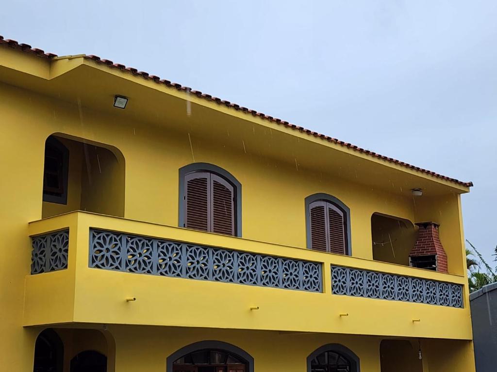 a yellow building with a balcony at Casa Peruibe frente a praia in Peruíbe