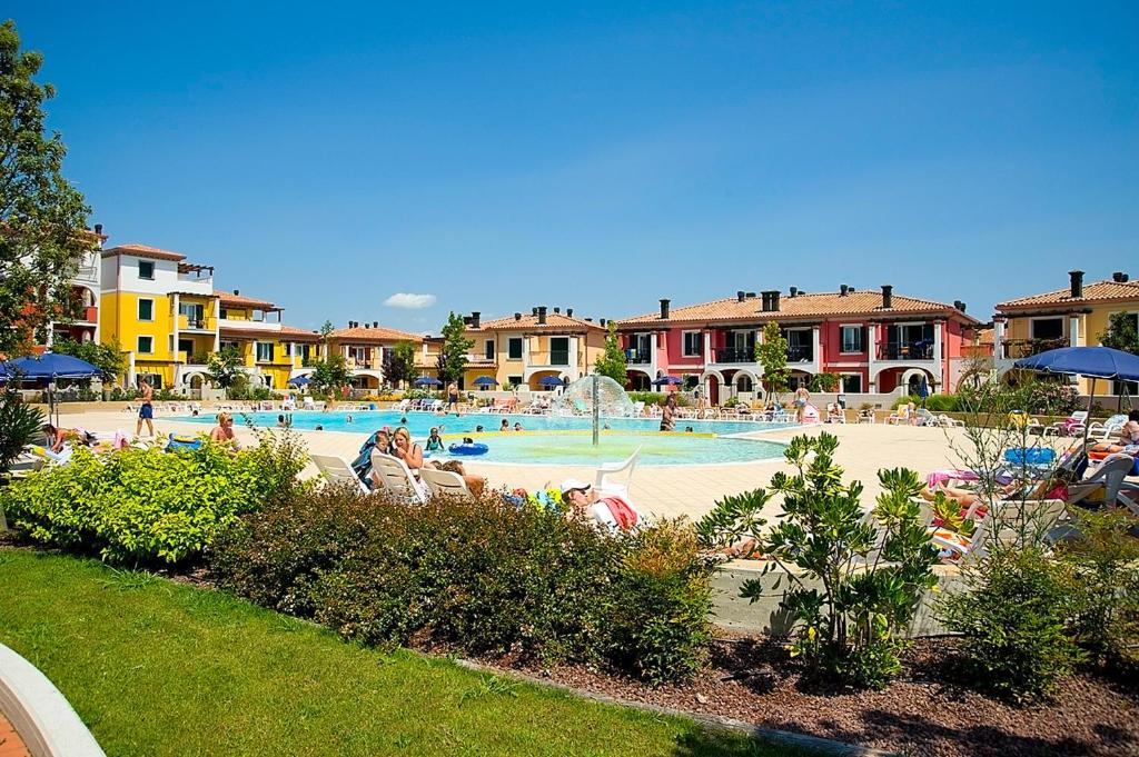 a resort with a swimming pool with people sitting in chairs at Villaggio Sant'Andrea in Caorle